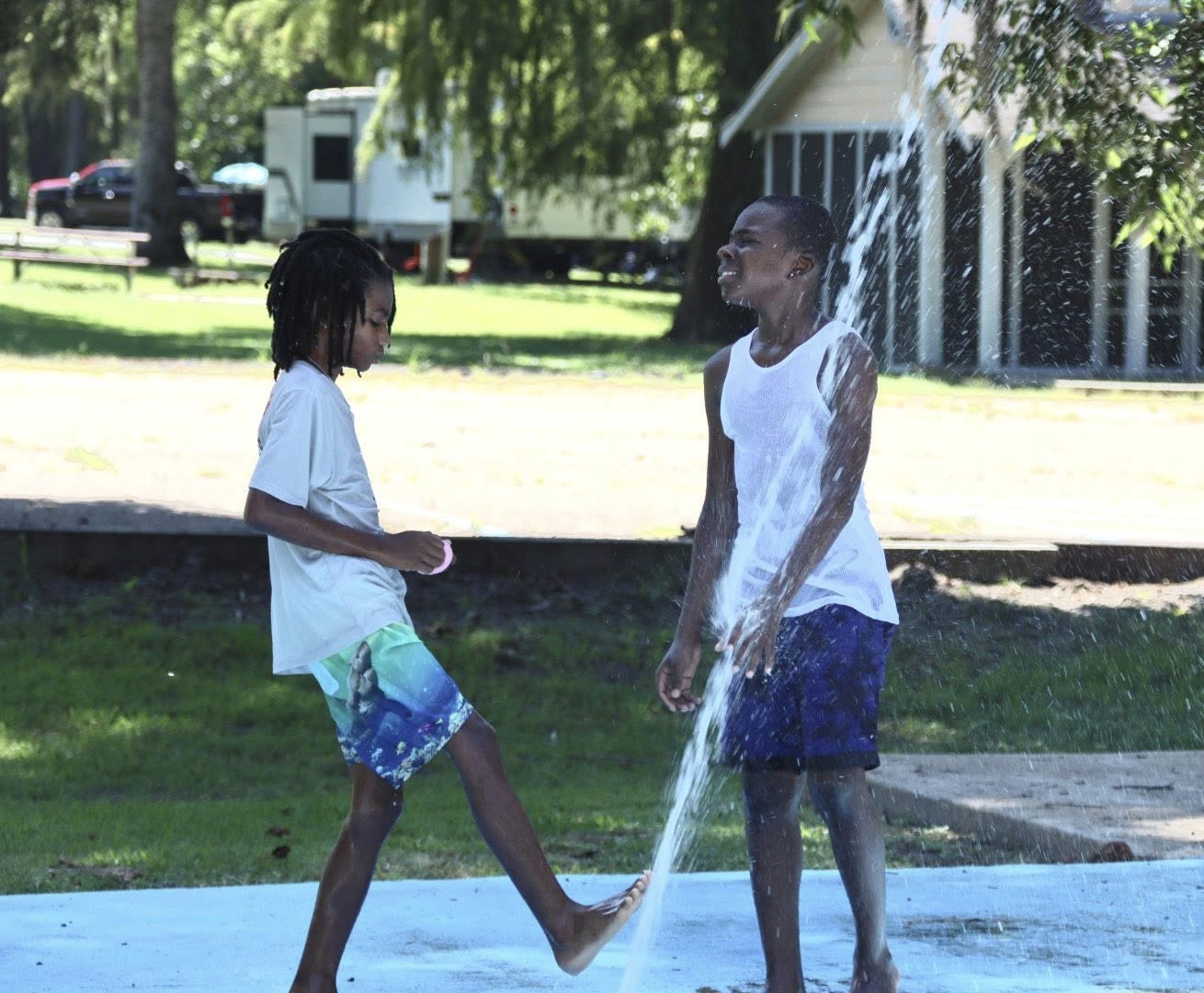 Two boys playing on a splash pad.